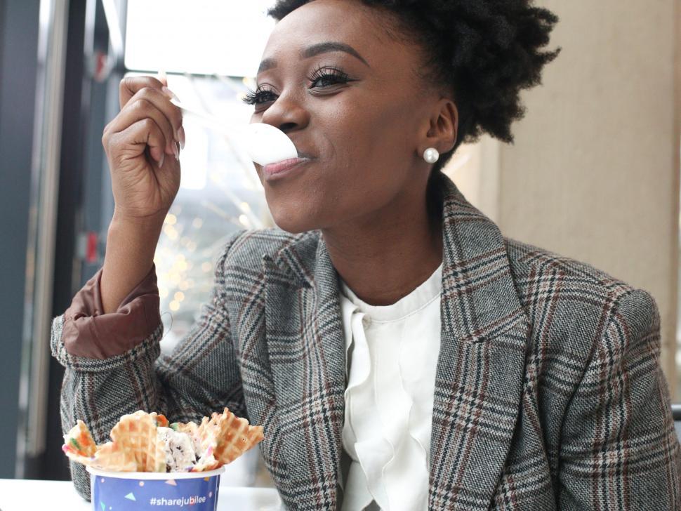 Free Image of Close up of Young woman in tweed blazer eating ice cream 