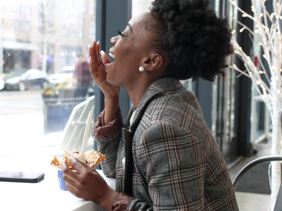 Free Image of Young professional woman in tweed blazer laughing and eating ice cream with spoon 