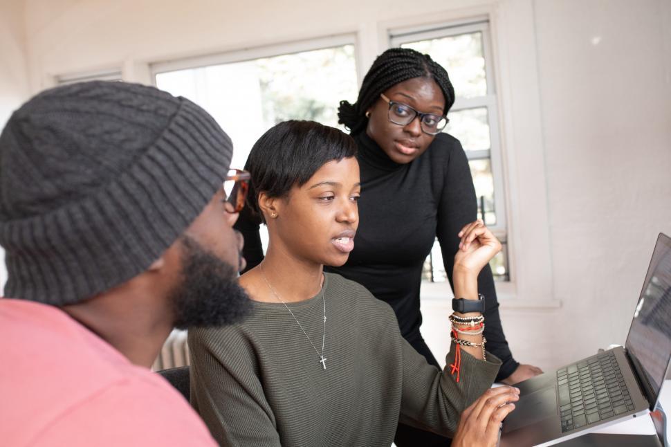 Free Image of Three Young Coworkers Working Together On Laptop in Office 