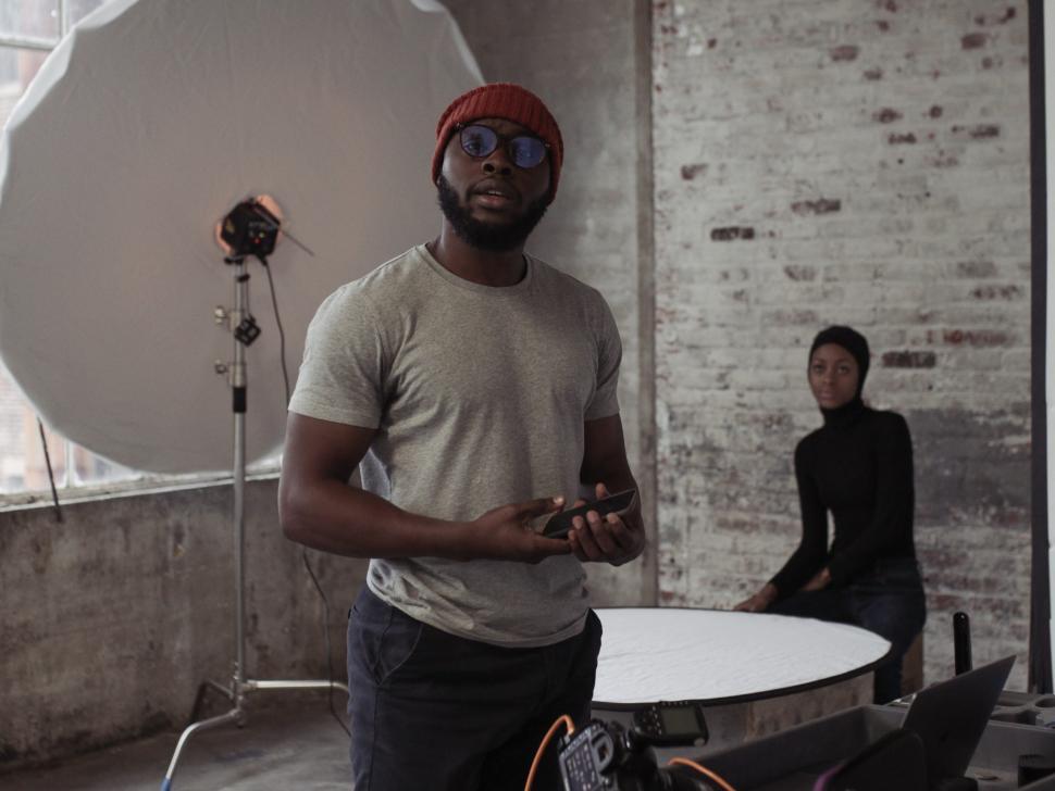 Free Image of Young Man With Cellphone and Female Model in a photo studio 