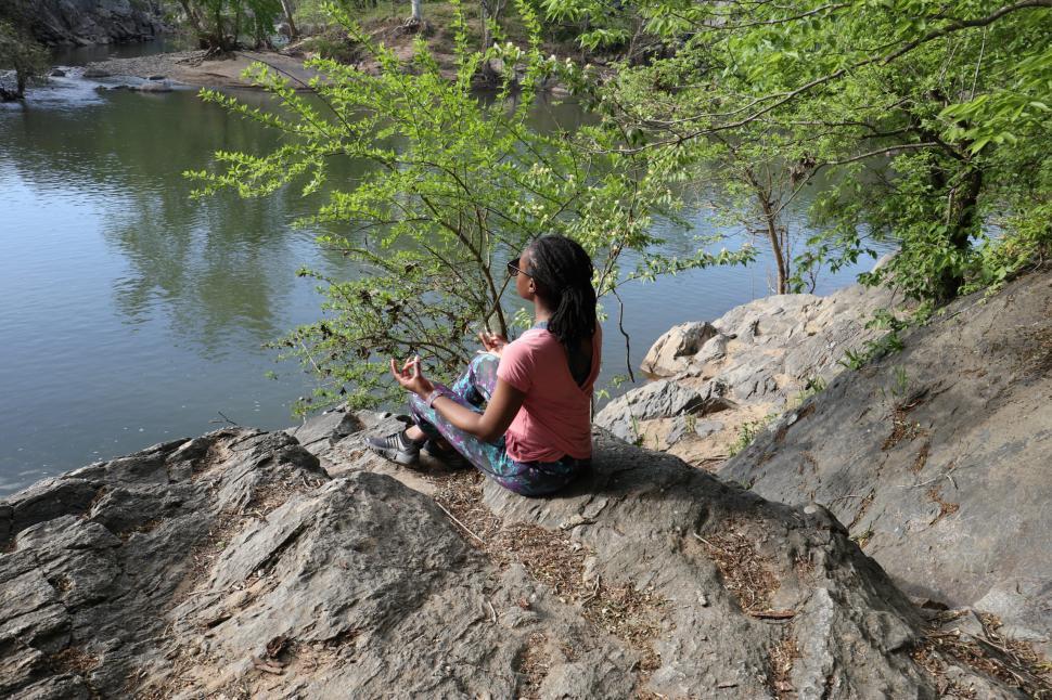 Free Image of Young Woman sitting in lotus yoga pose near lake 