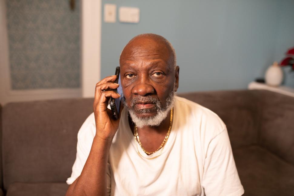 Free Image of Older Man talking on smartphone at home - looking at camera 