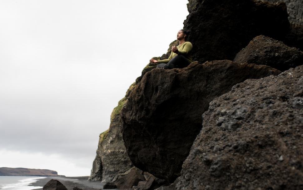 Free Image of View of Young Woman meditating on mountain with river and sky 