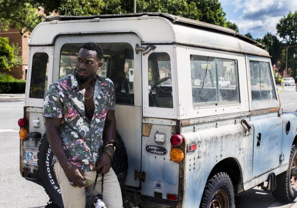 Free Image of Young man and old land rover car on road - looking away 