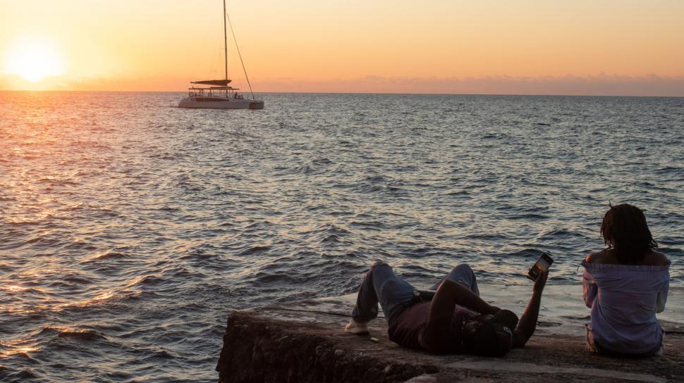 Free Image of Silhouette View of man and woman relaxing at seashore 