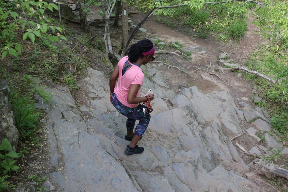 Free Image of Young Woman in yoga pants using rock stairs with trees in the forest 