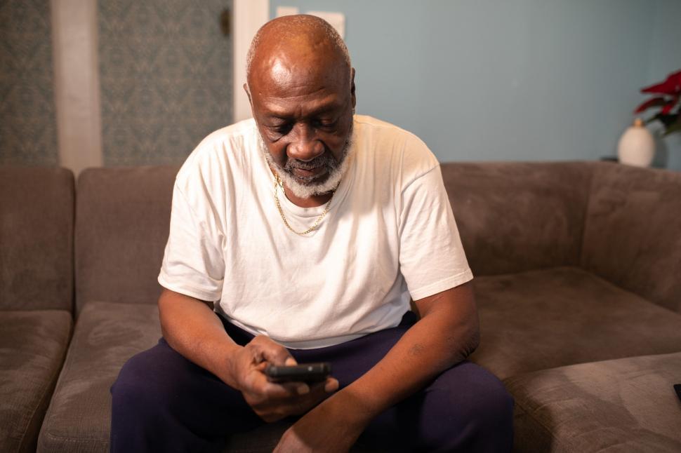 Free Image of Older Man in white shirt holding smartphone at home 