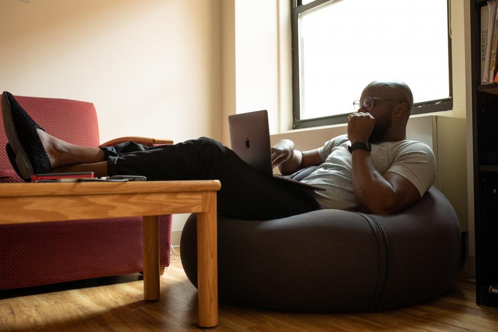 Free Image of Young Man sitting on bean bag chair at home 