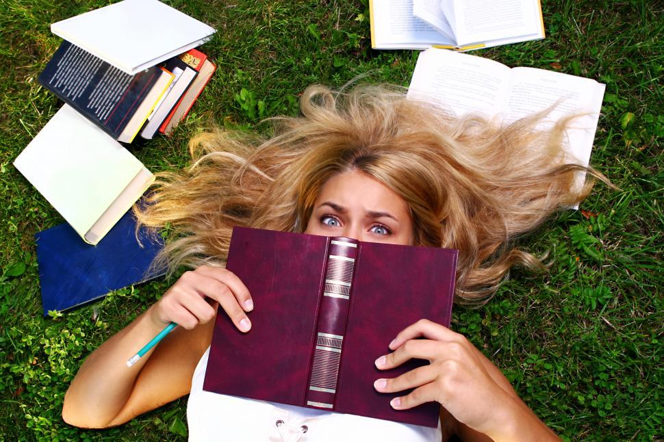 Free Image of Overworked young student hiding behind open book 