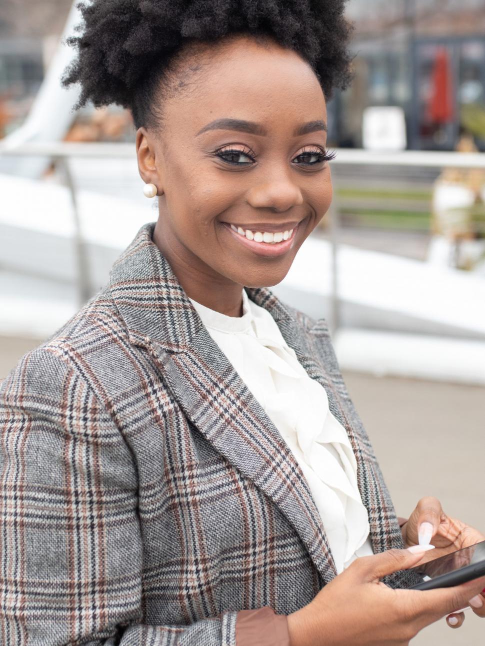 Free Image of Young smiling business woman in tweed blazer, with smartphone 