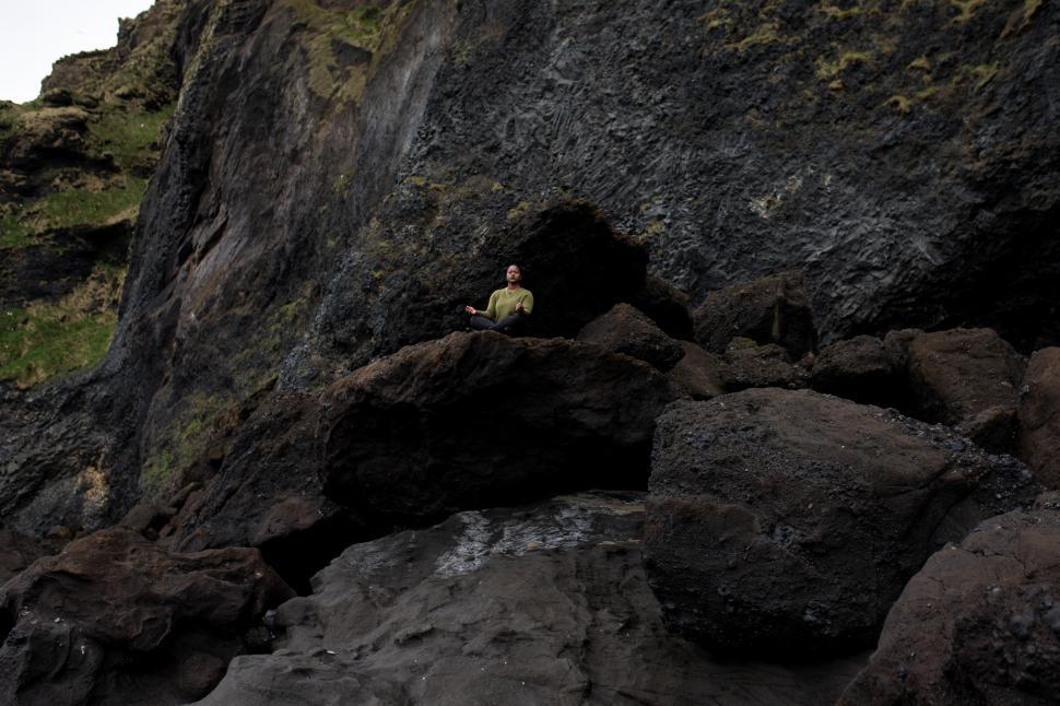 Free Image of Young Woman meditating in cross-legged position on mossy mountai 