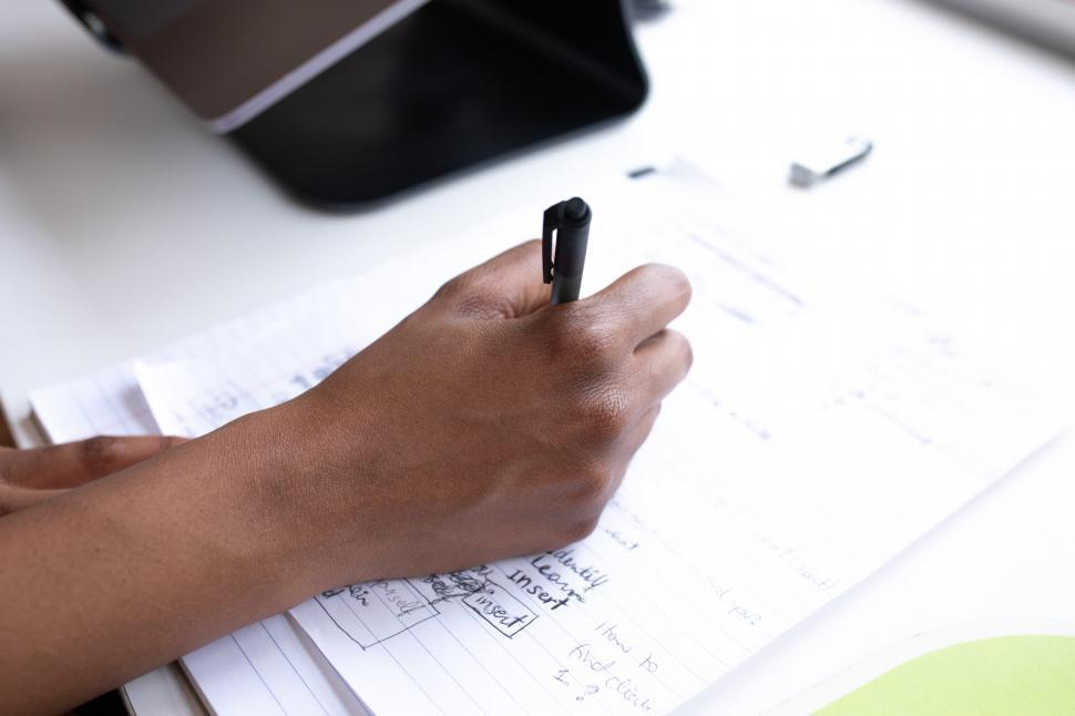 Free Image of Businesswoman writing on paper with pen 