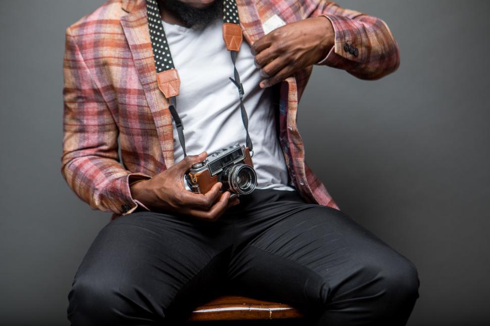 Free Image of Unrecognizable photographer sitting on chair with vintage camera 