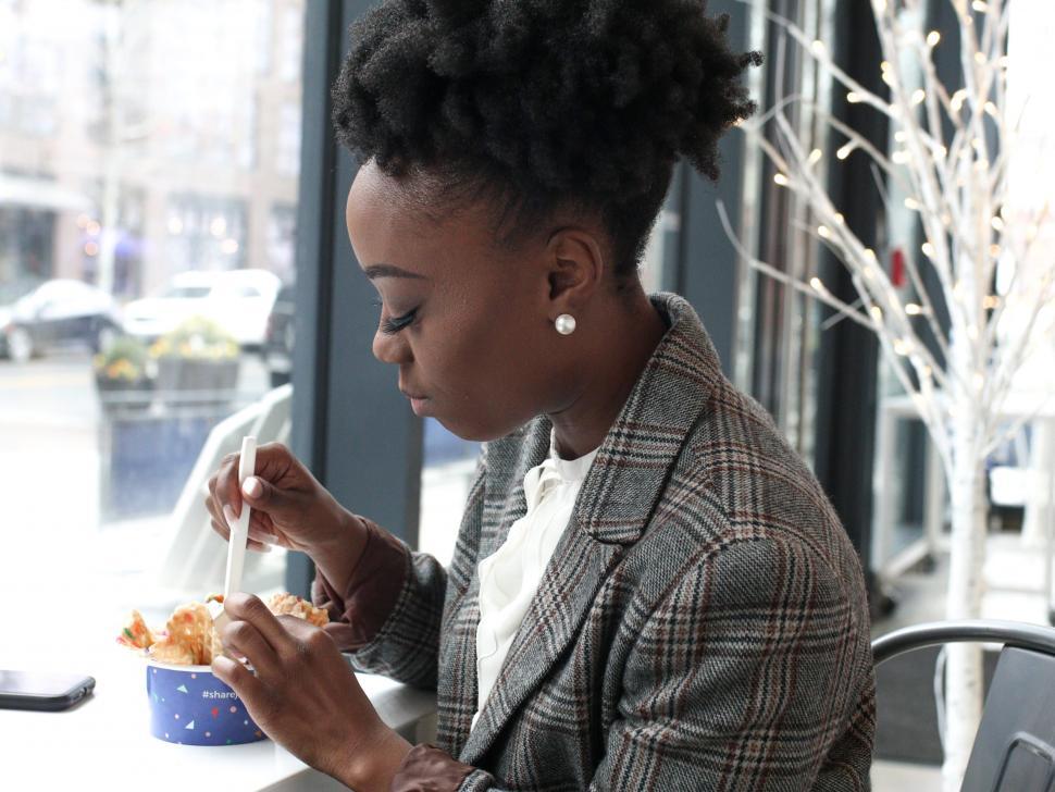 Free Image of Young woman in pearl earrings eating ice cream with spo 