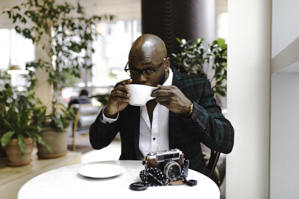 Free Image of Young well-dressed man in spectacles holding a coffee cup with camera 