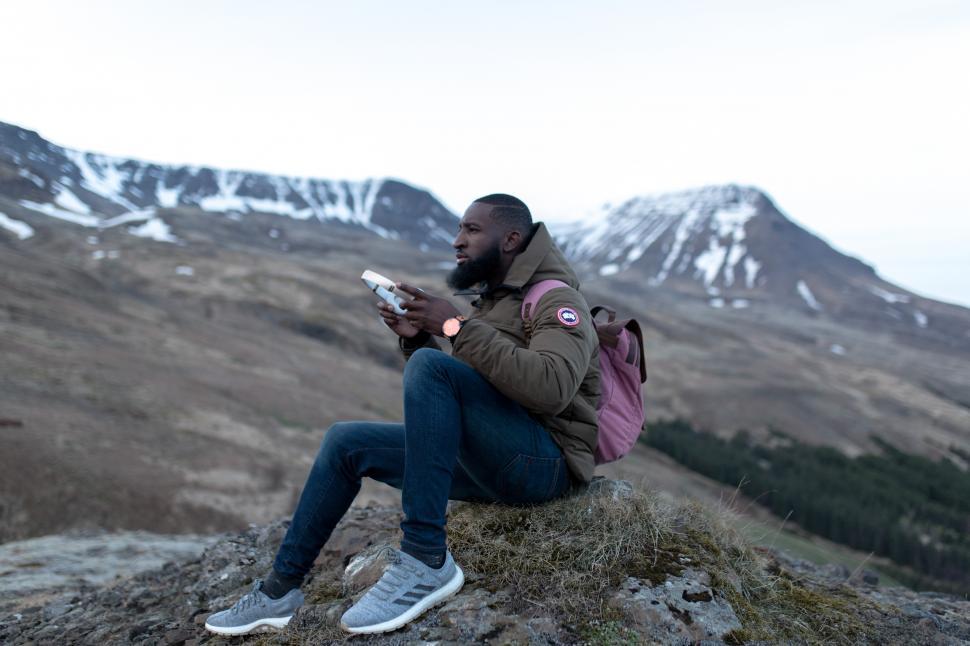 Free Image of Young Man in Green Winter Jacket Sitting Alone on Mountain 