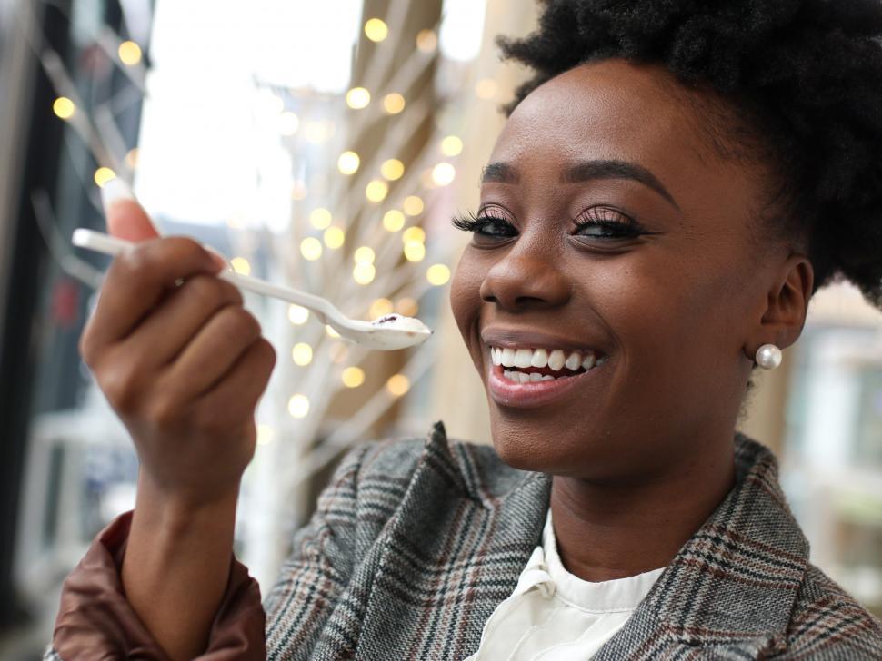 Free Image of Young business woman in tweed blazer eating ice cream with spoon 