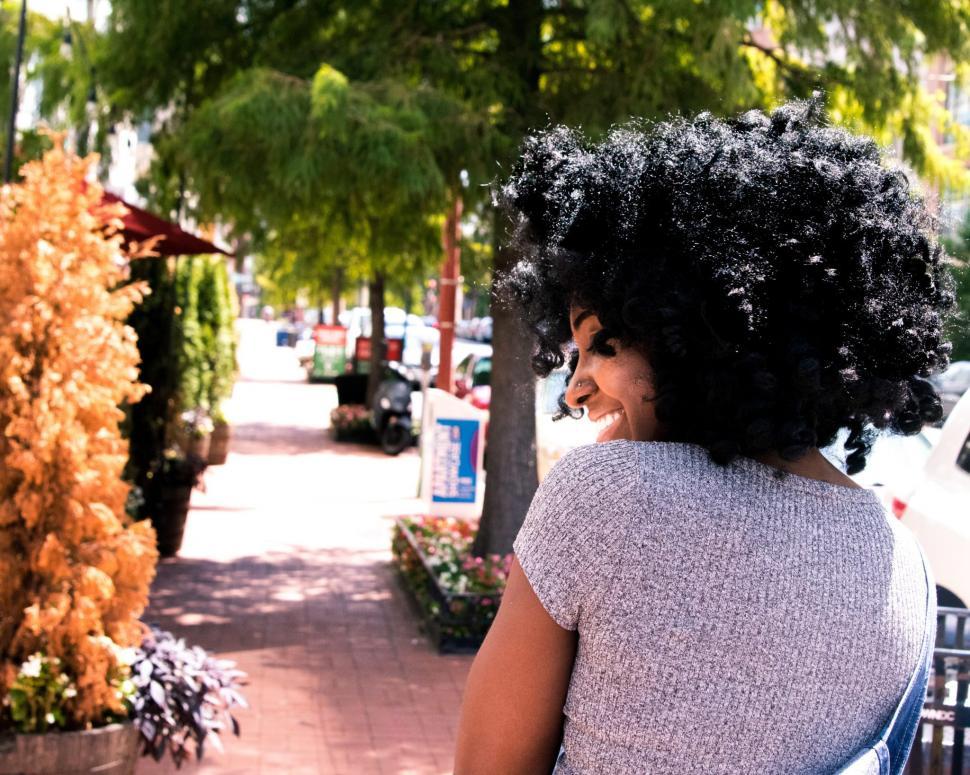 Free Image of Young Woman in grey t-shirt and dungarees with flowers on the pa 