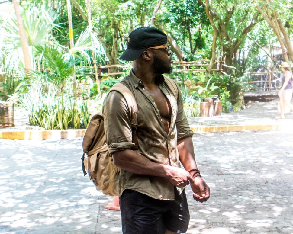 Free Image of Young Man in Green Shirt and beige backpack - looking away 
