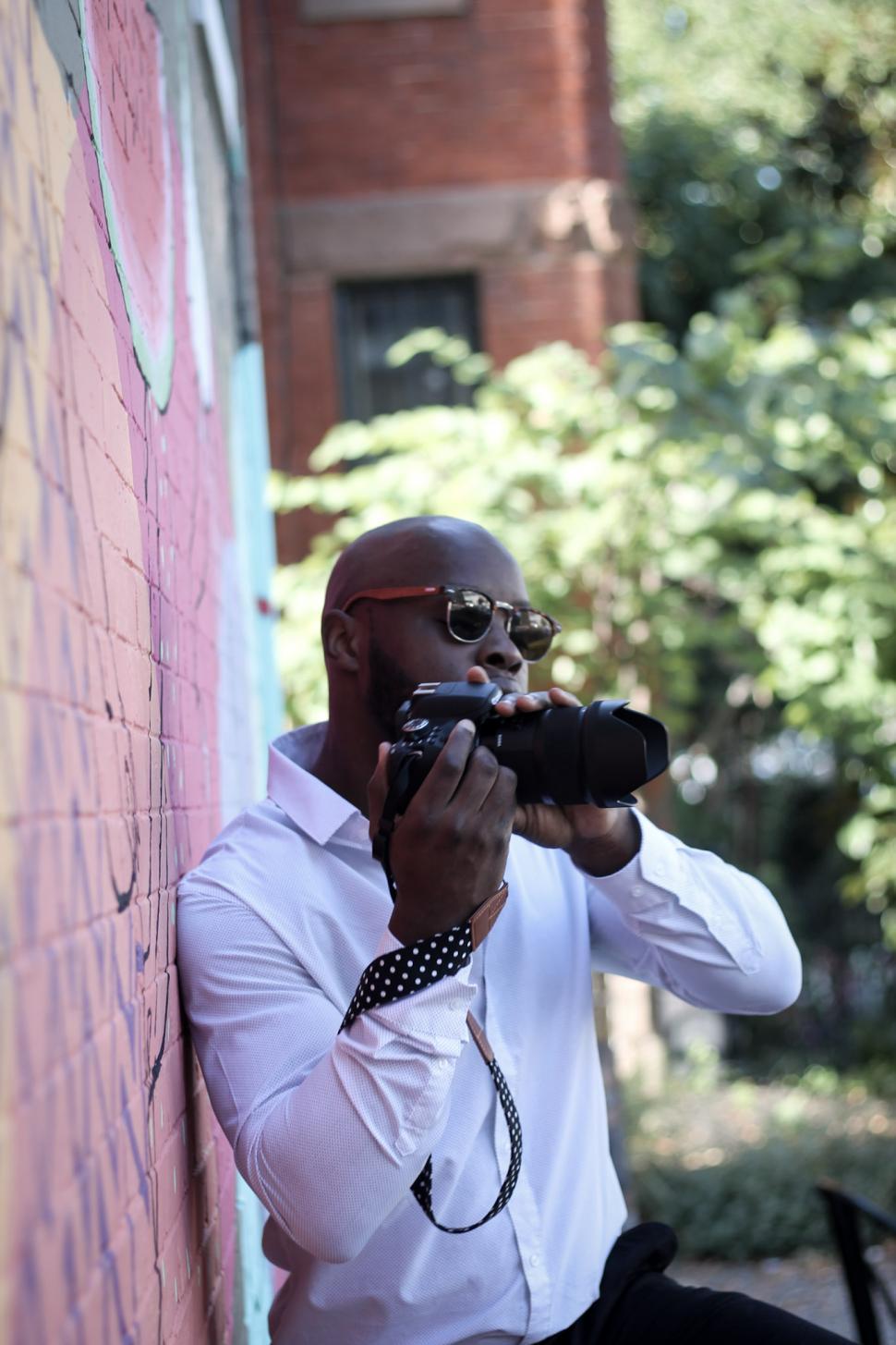 Free Image of Young Photographer in white shirt holding professional DSLR camera 