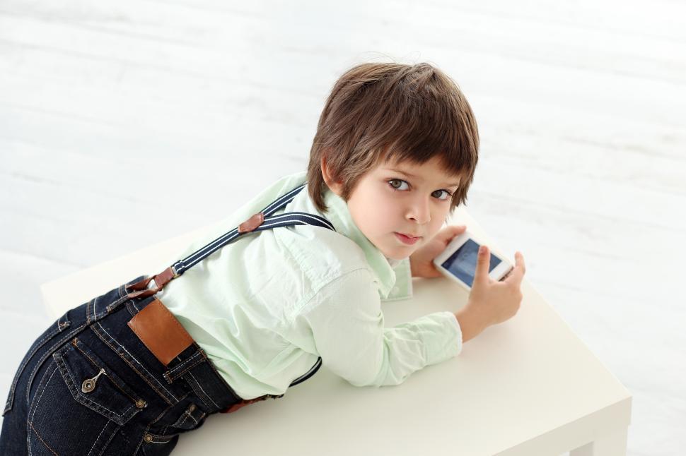 Free Image of Adorable kid looking up from his phone 