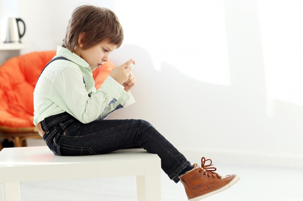 Free Image of Adorable kid engrossed in smartphone 