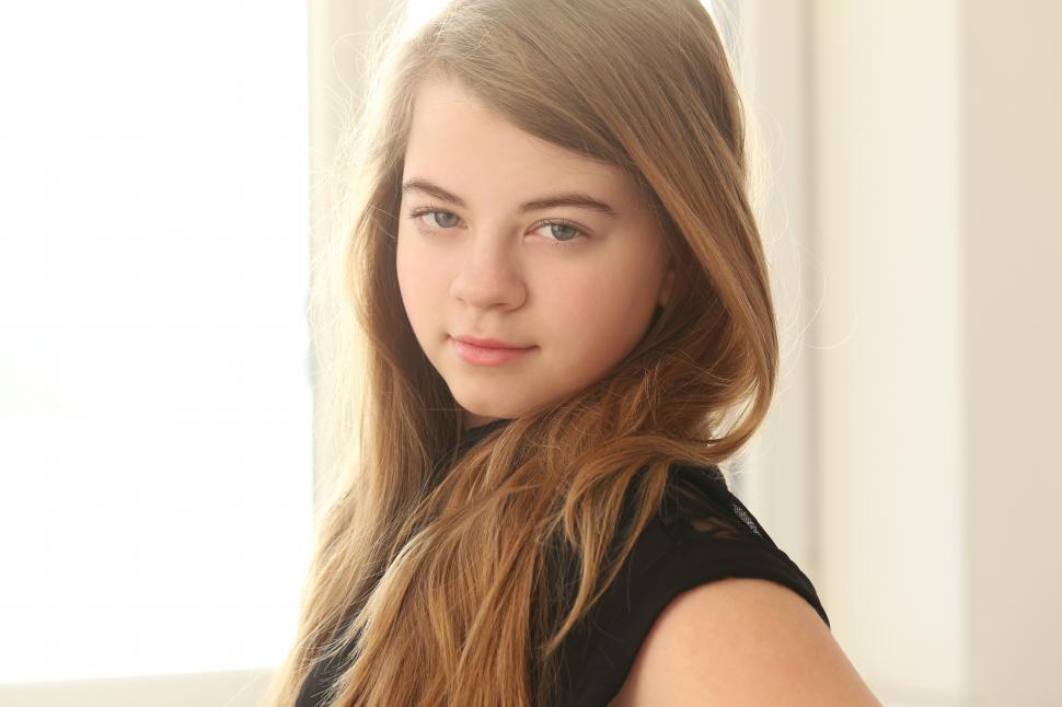 Free Image of Teenage girl with long hair in warm light, looking at camera 