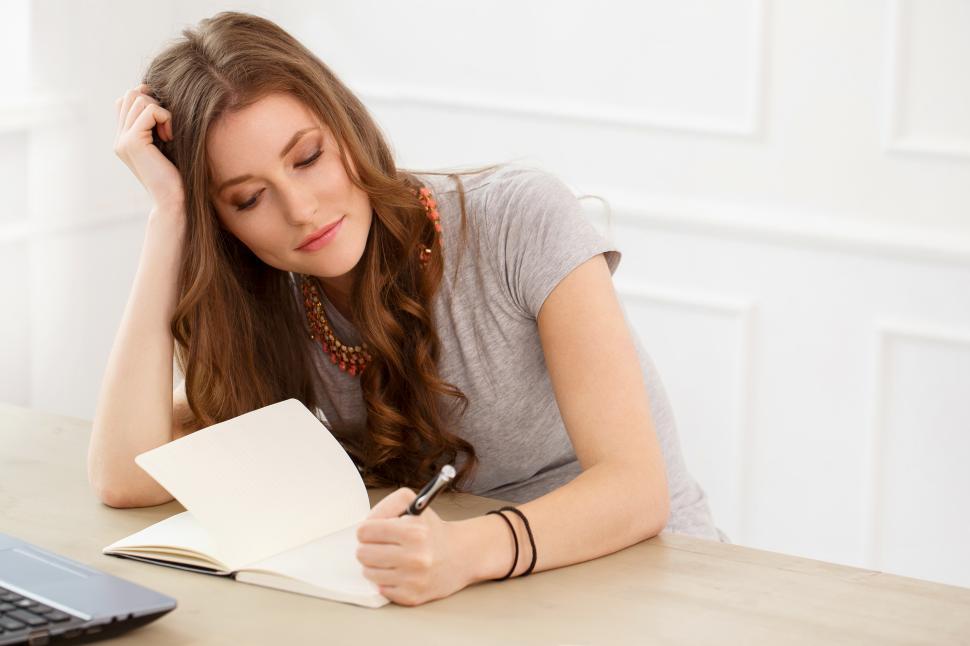 Free Image of Student. Attractive girl by the table writing 