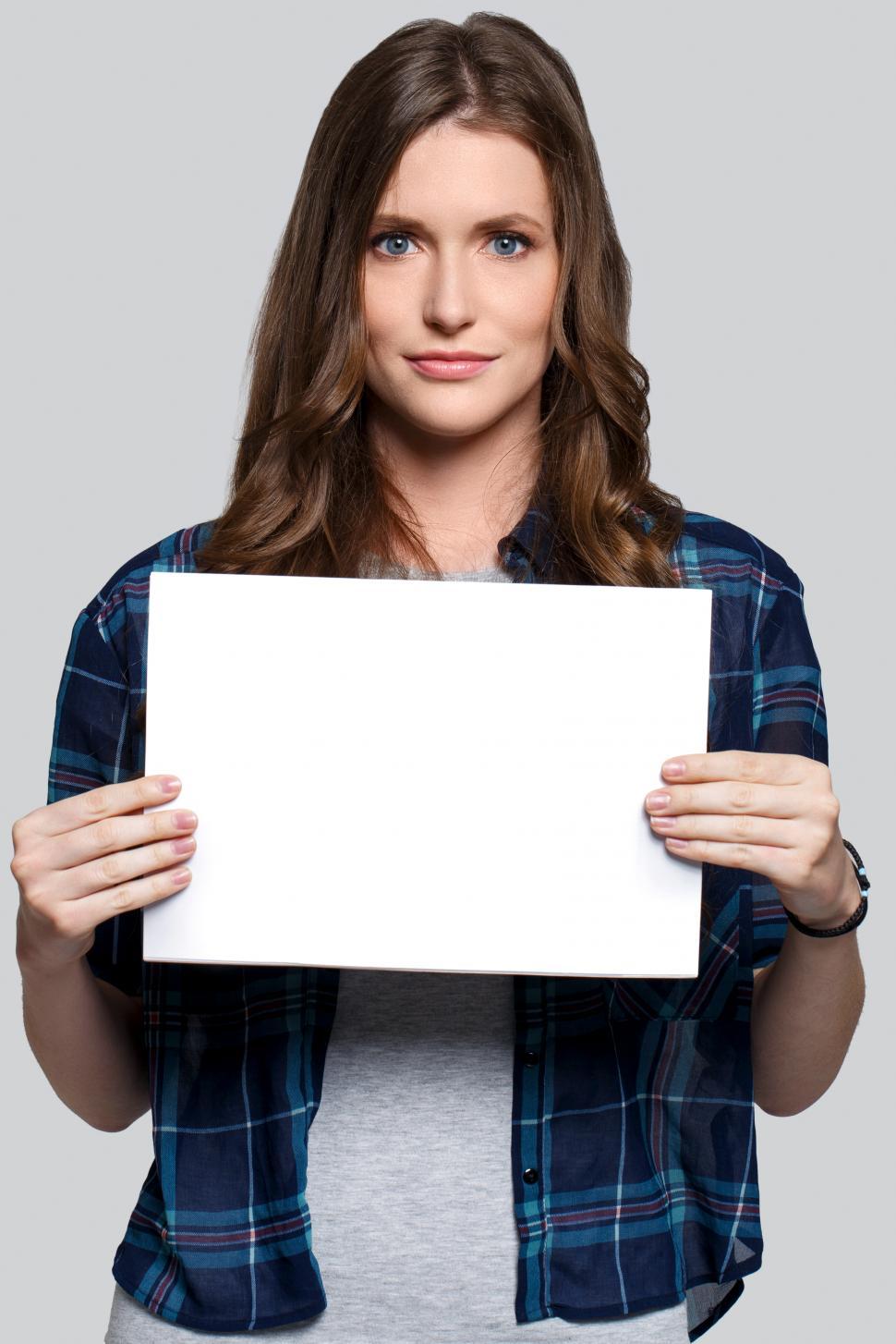 Free Image of Girl holding white billboard, looking serious 