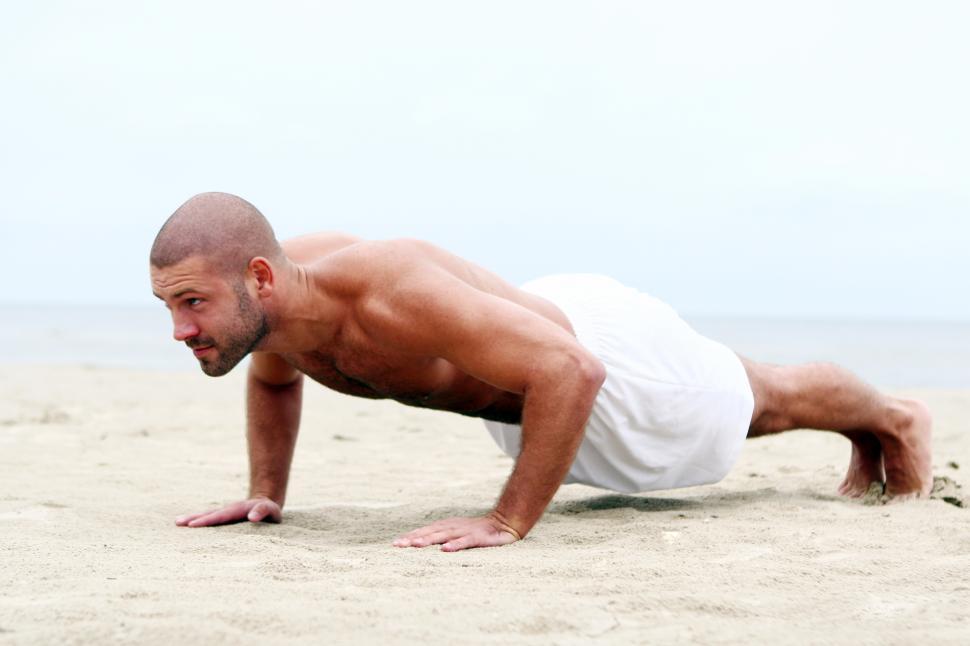 Free Image of Fit man doing pushups on the beach 