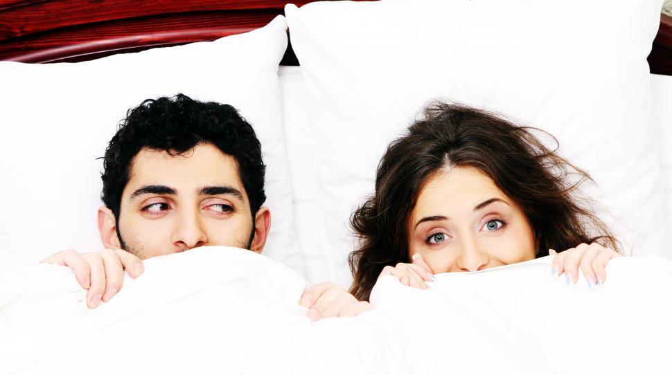 Free Image of Young couple in bed with covers pulled up 