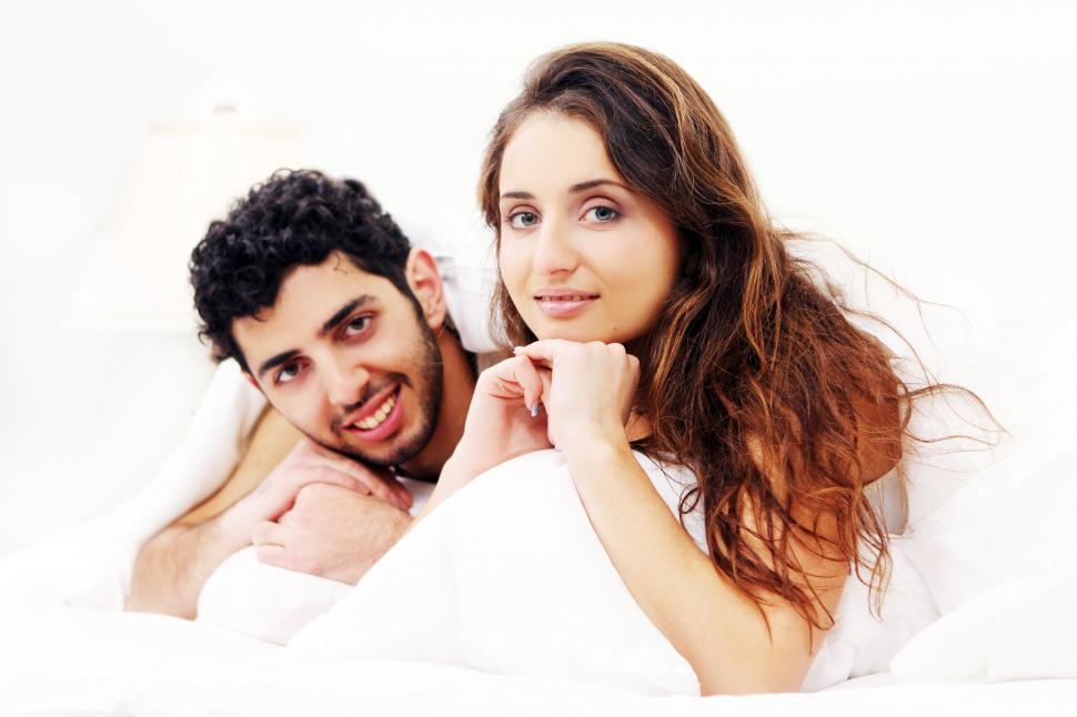 Free Image of Young couple sitting up in bed 