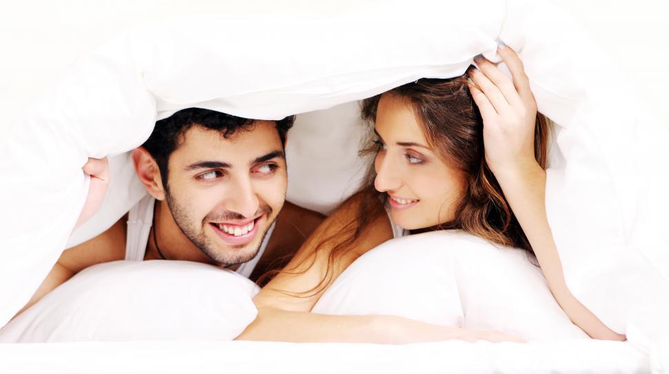 Free Image of Young couple under the covers together 