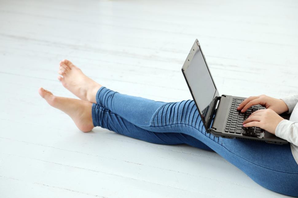 Free Image of Girl on the ground with a laptop, typing away 