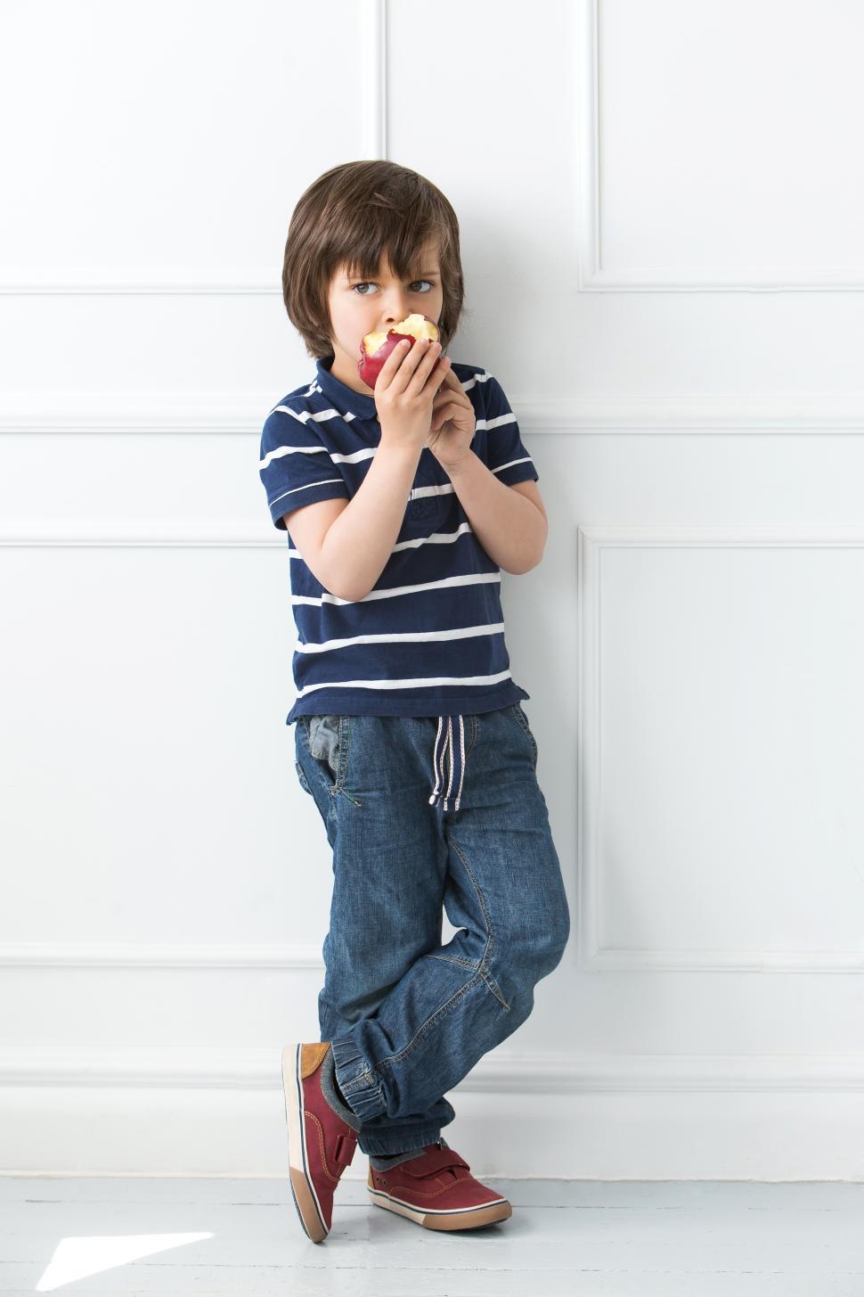 Free Image of Adorable kid standing and eating apple 