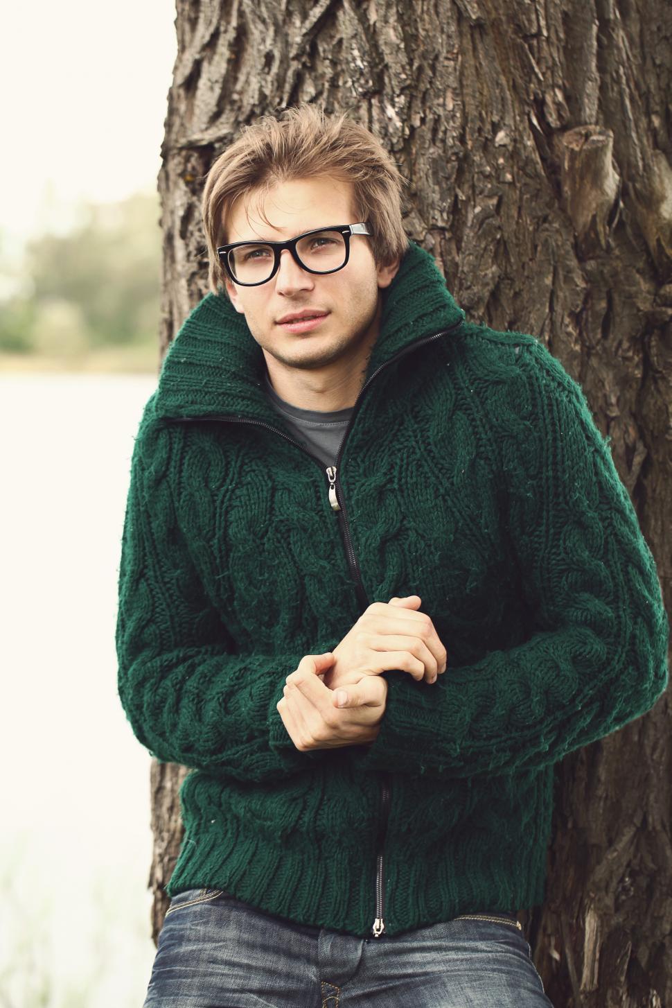 Free Image of Man in sweater outdoors against tree 