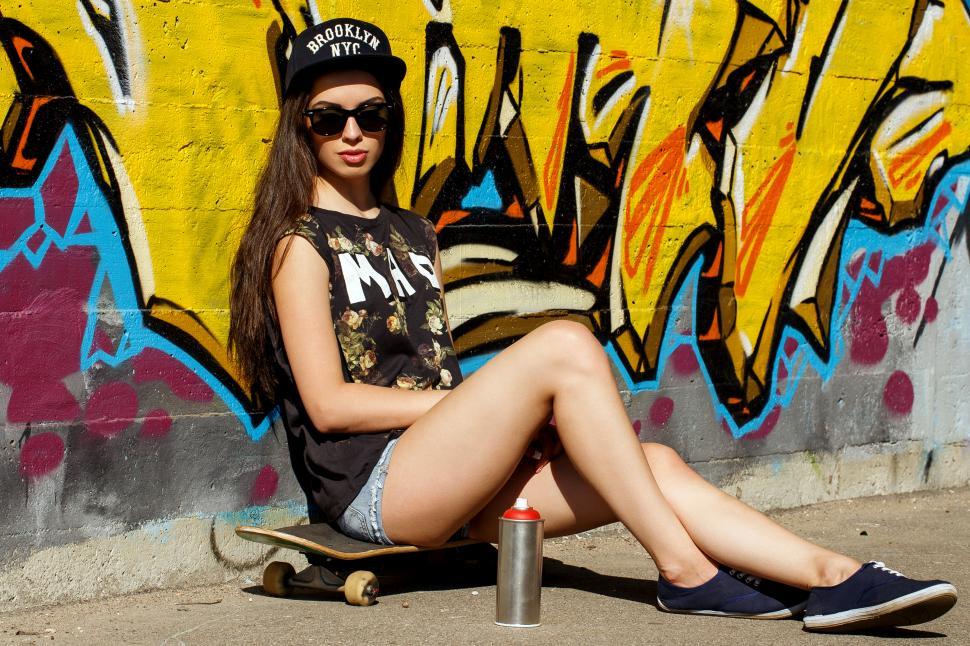 Free Image of Skater girl on the street against painted wall 
