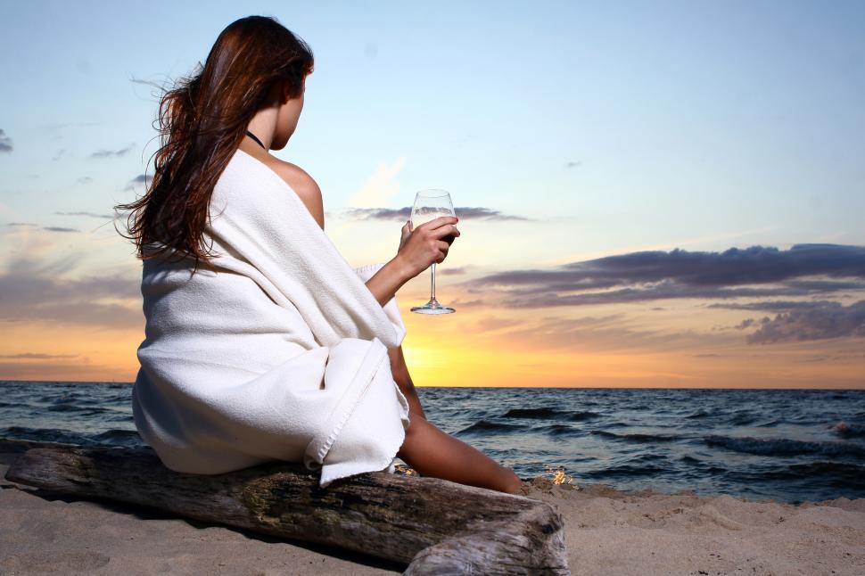 Free Image of Woman sitting wrapped up on the beach 