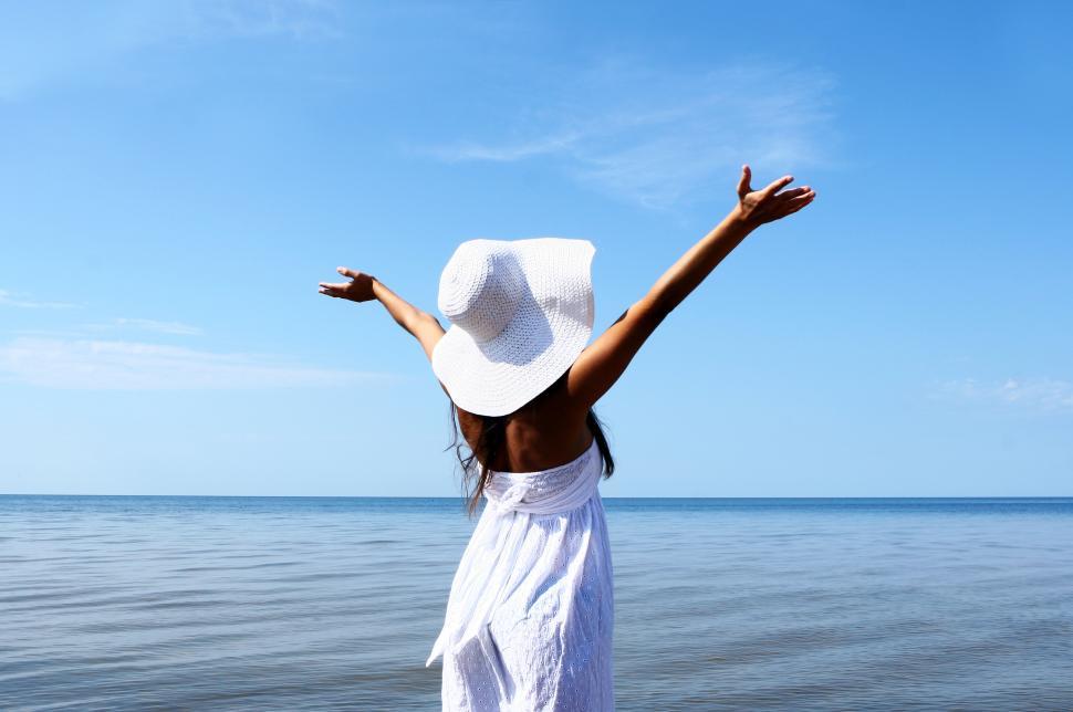 Free Image of Young woman in the water with arms in the air 