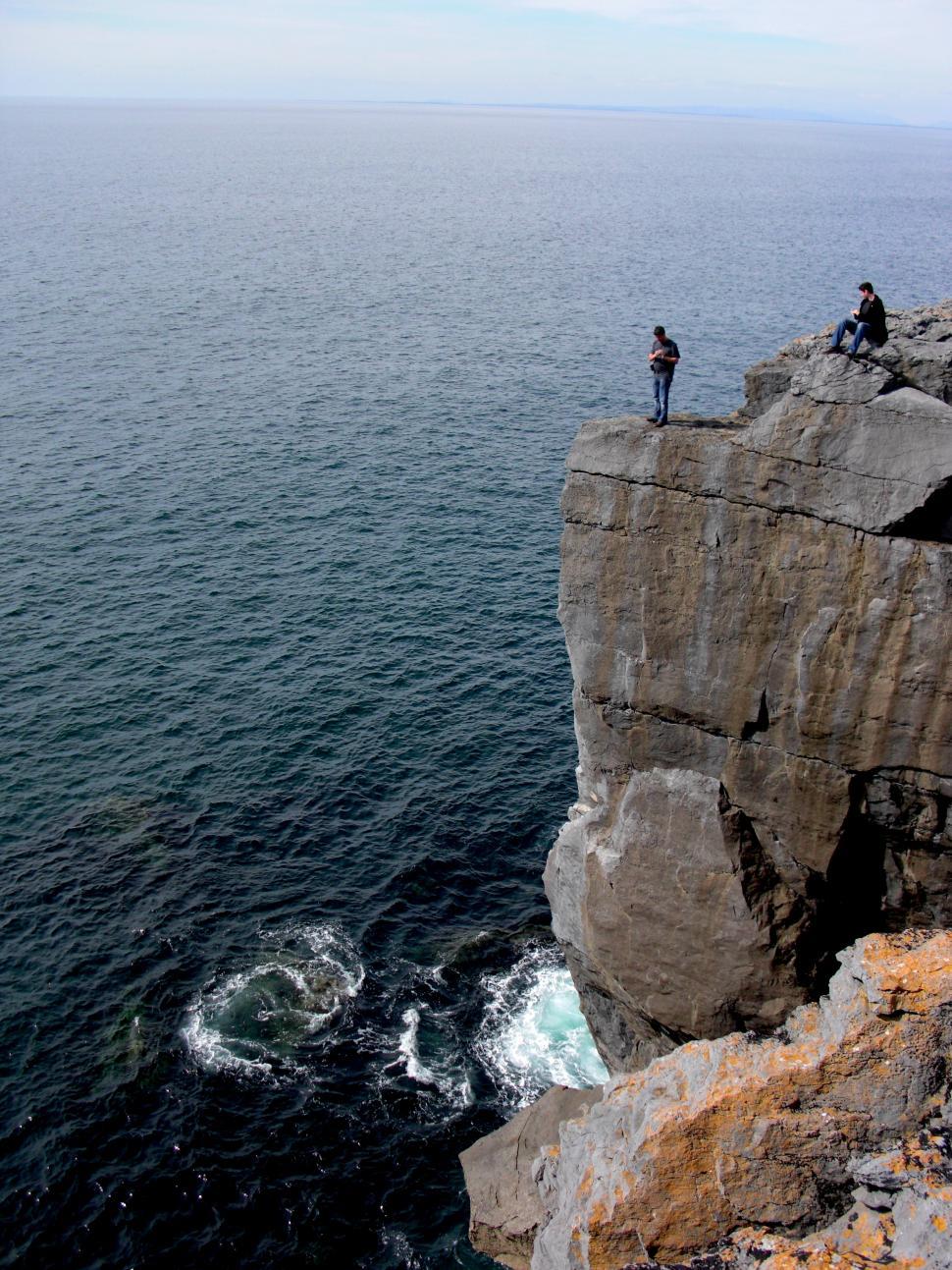 Free Image of Couple Standing on Cliff Overlooking Ocean 