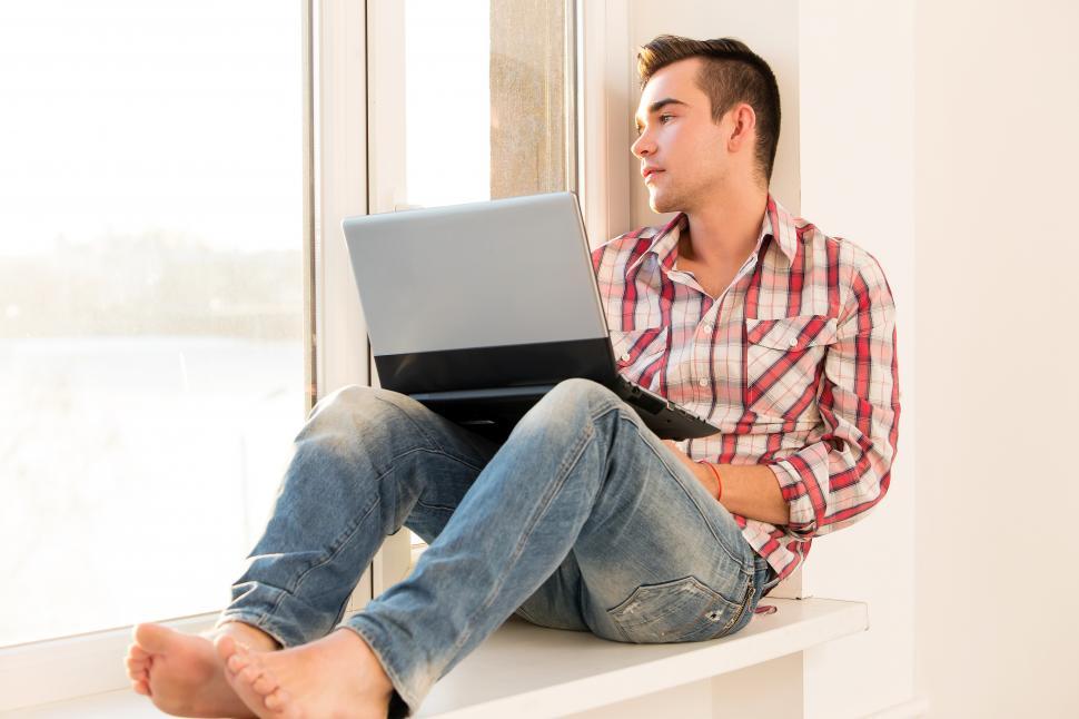 Free Image of Barefoot guy looking out the window 