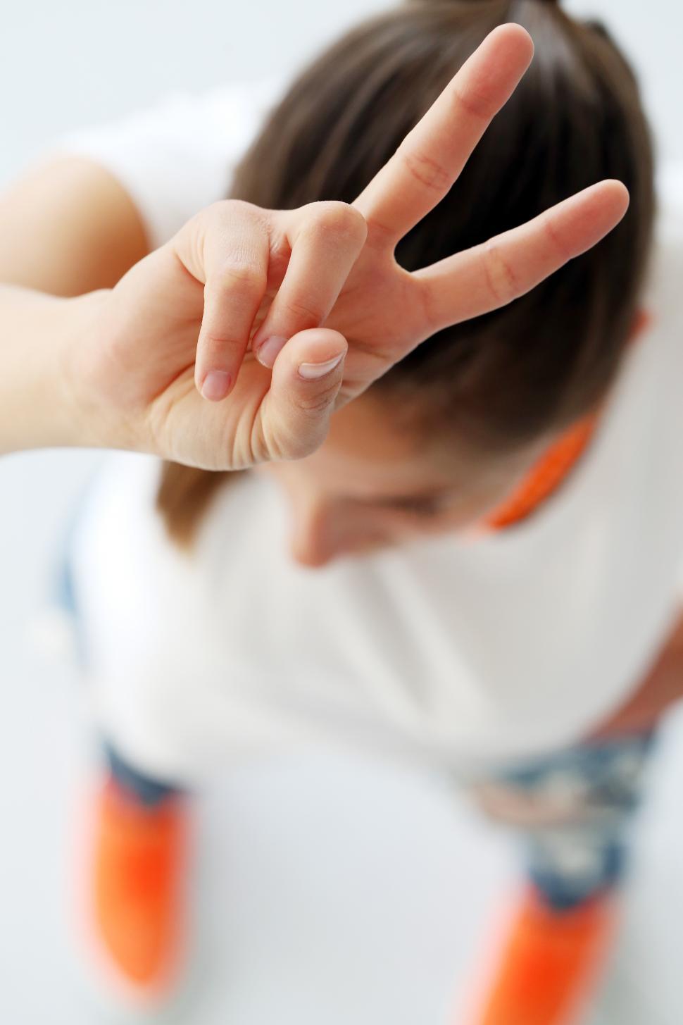 Free Image of Woman holding two fingers up over her head 
