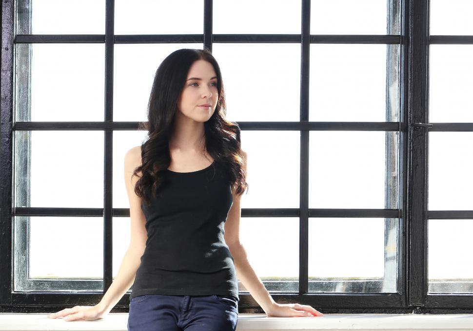 Free Image of Girl leaning against a bright window 
