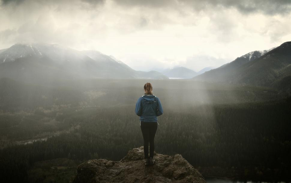 Free Image of Hiker on Rock Ledge over Foggy Dark Landscape 