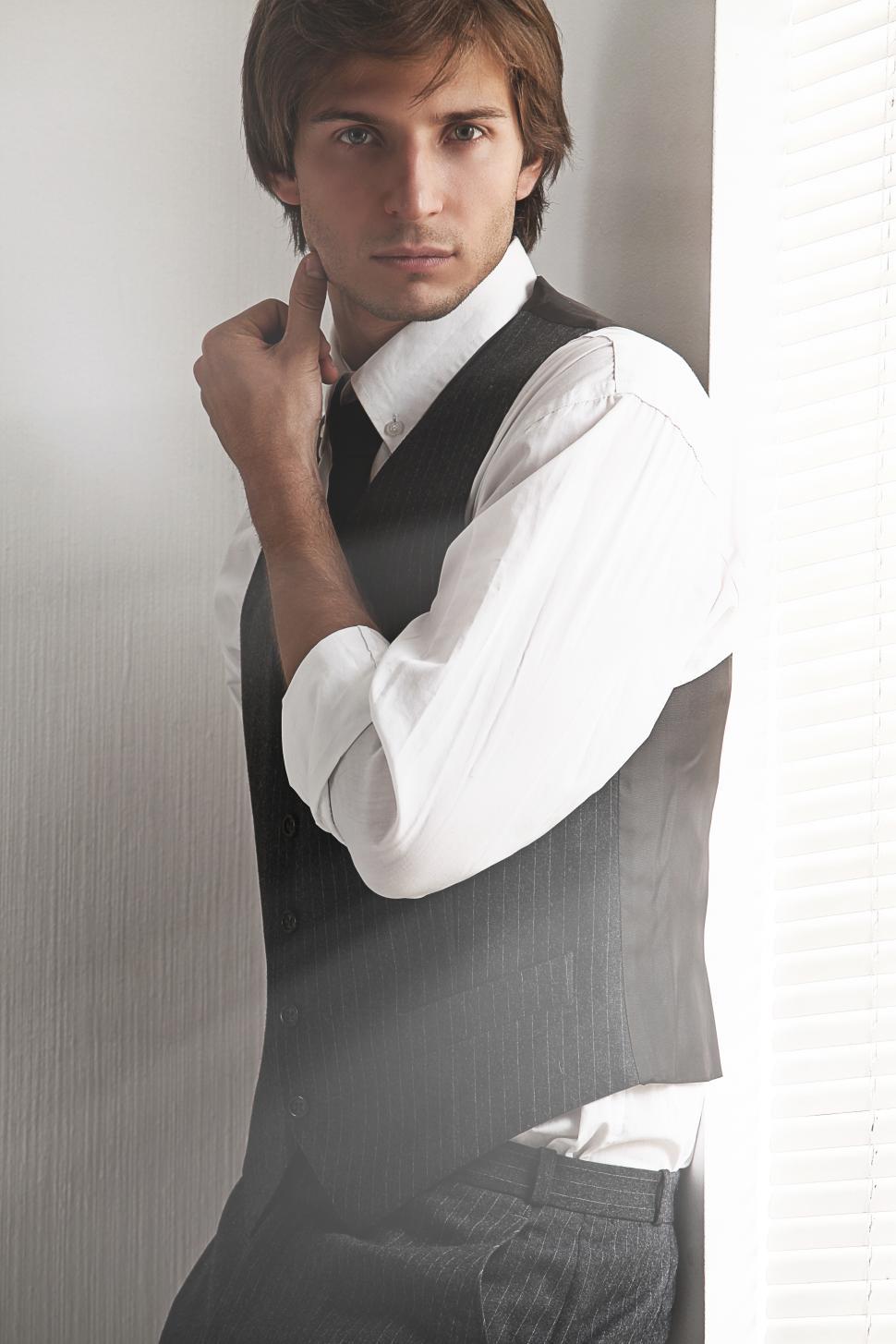 Free Image of Attractive man standing next to a bright window 