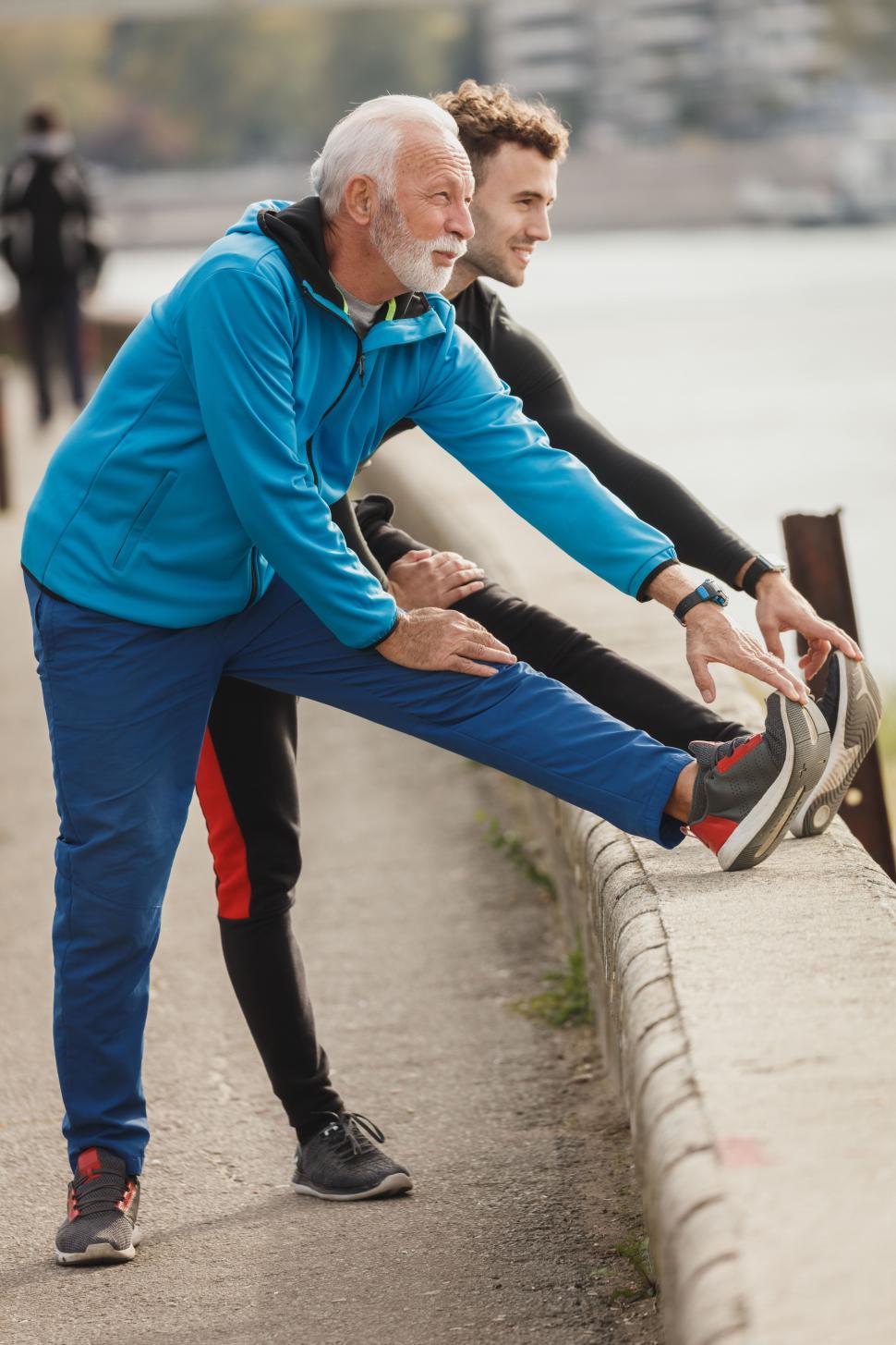 Free Image of Senior man with young man doing toe touch exercise on the bridge 