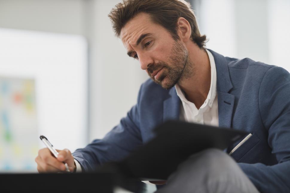 Free Image of Male office worker checking papers with pen in office 
