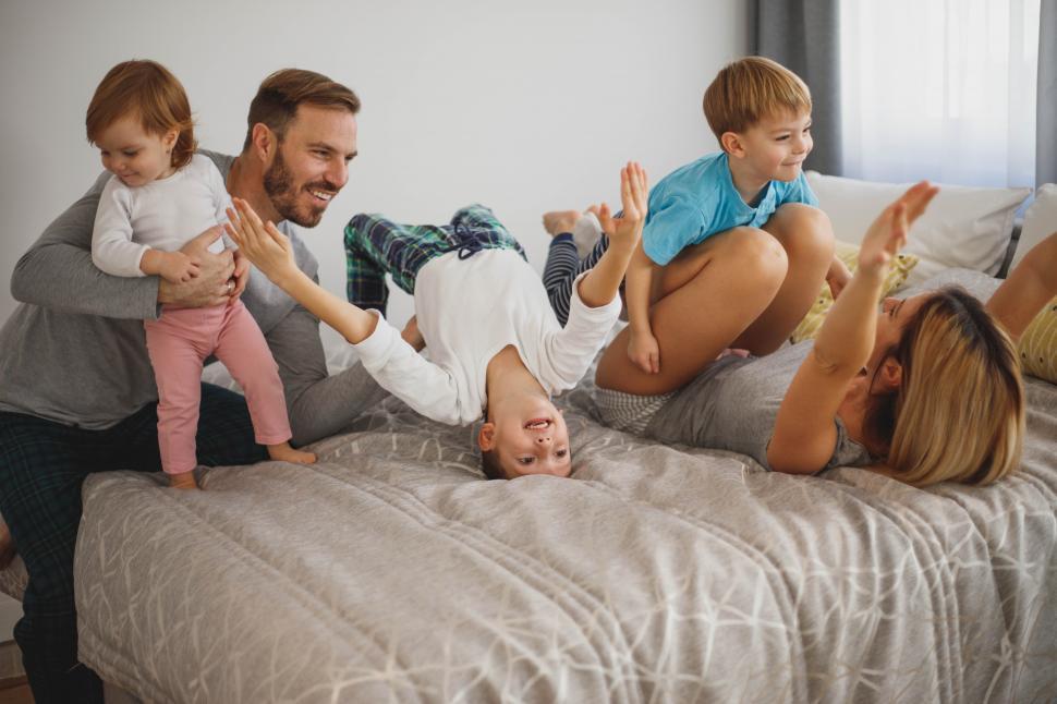 Free Image of Happy family playing on bed, fun family time 