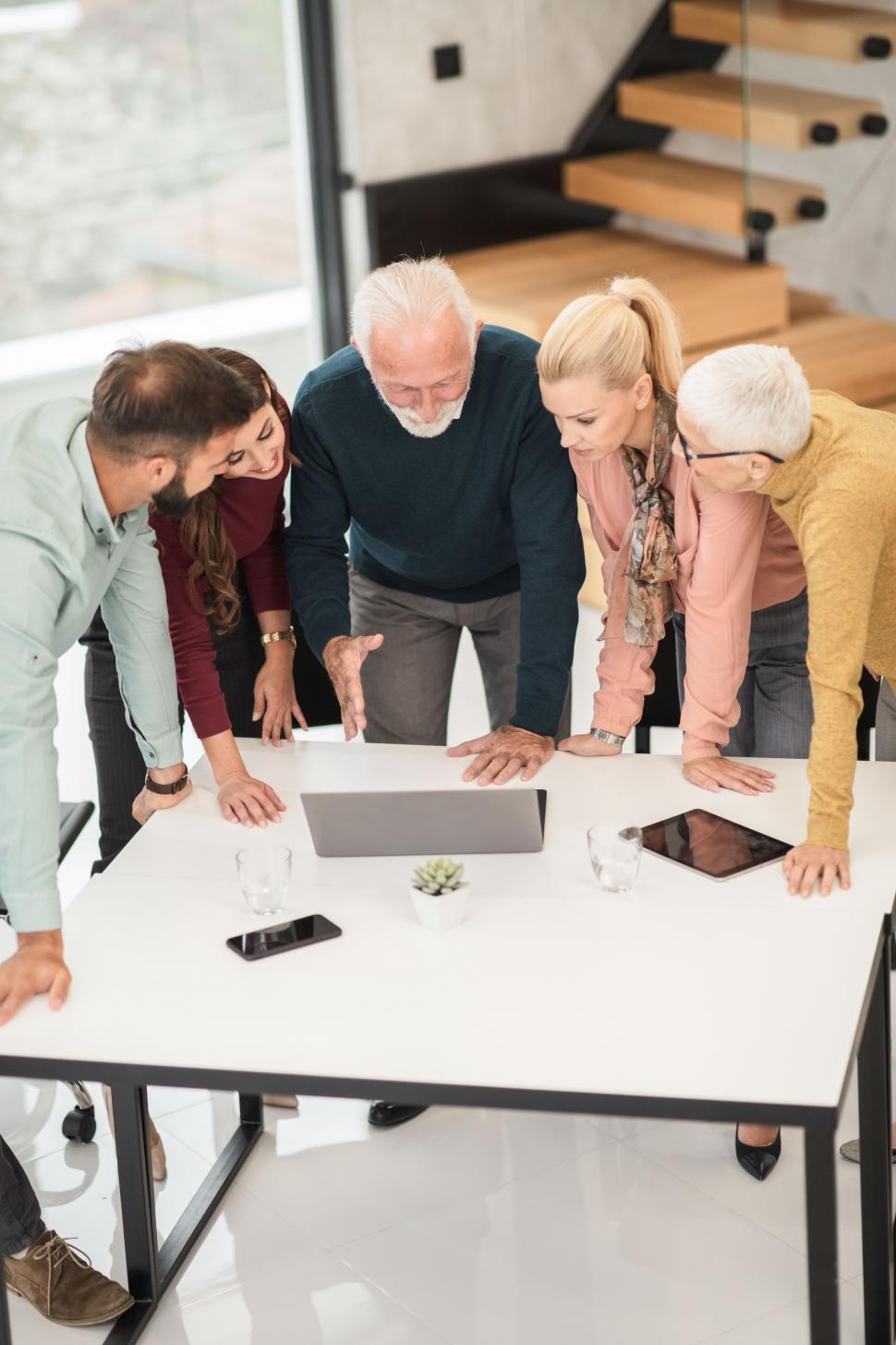 Free Image of Office workers with senior man in center, discussing in a meeting 