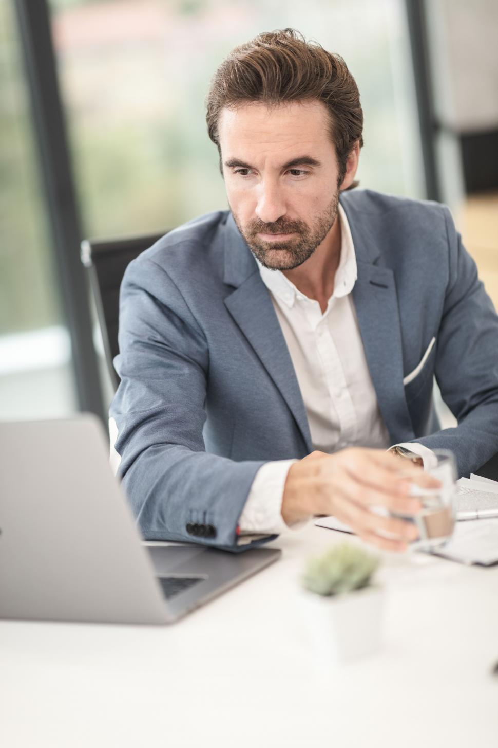Free Image of Male office executive working on laptop and drinking water 